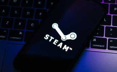 closeup shot of a phone placed on top of a laptop keyboard previewing the steam app logo