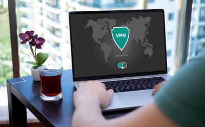 person interacting with a laptop with a screen previewing a generic VPN interface