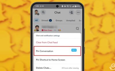 phone showing a preview of the Pin conversation feature on the Snapchat app with a blurred yellow background consisting of scattered snapchat logos