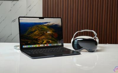 shot of the Apple Vision Pro next to a MacBook both placed on a desk