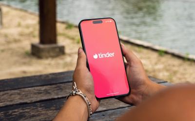 person holding a phone with the Tinder app loading screen