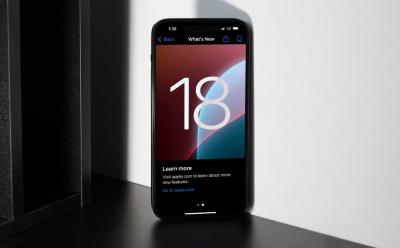iOS 18 banner on an iPhone placed upright on a desk
