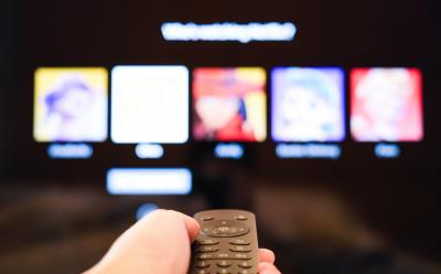 person holding remote in front of a TV with Netflix profiles screen