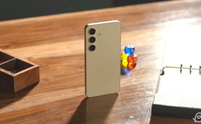 Samsung Galaxy S24 Amber Yellow variant placed upright on a wooden desk