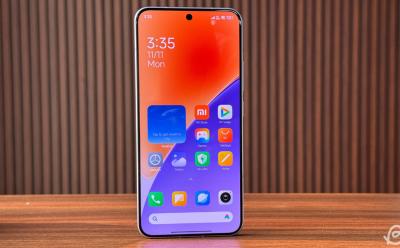 Xiaomi 15 placed upright on a flat surface in front of a striped brown background