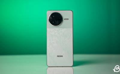 Redmi K80 Phone in Mint colorway placed upright on a desk with a green background