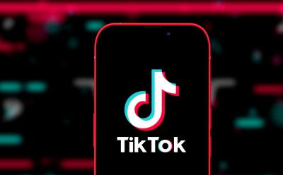 phone with TikTok logo in front of a blurred black background with pink and green elements