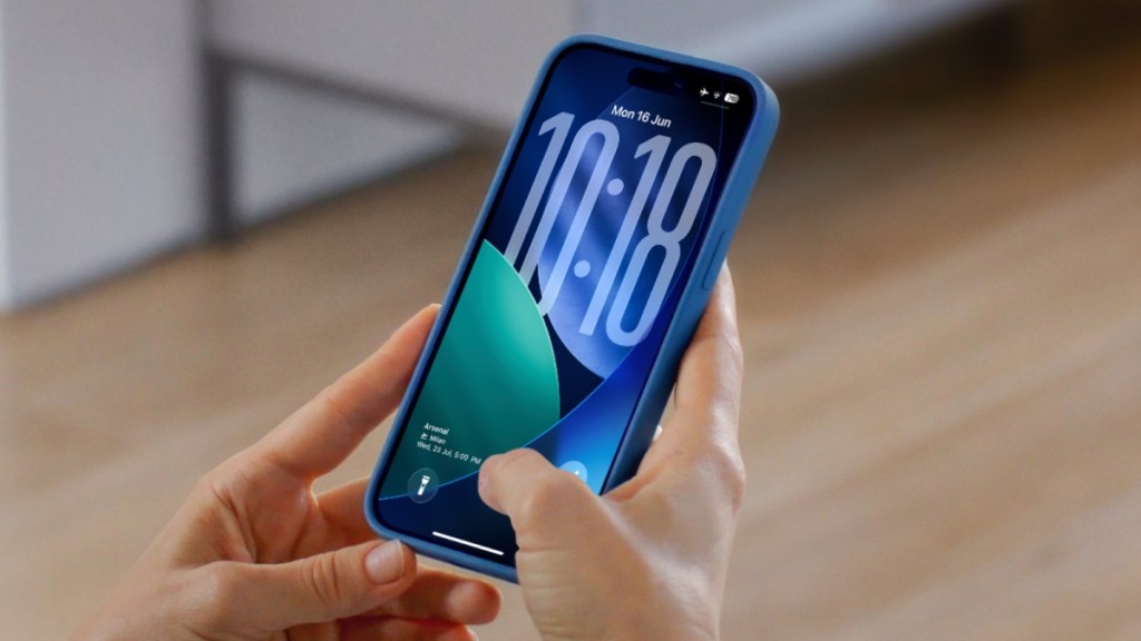 hand holding an iPhone previewing the iOS 26 lock screen in dark mode