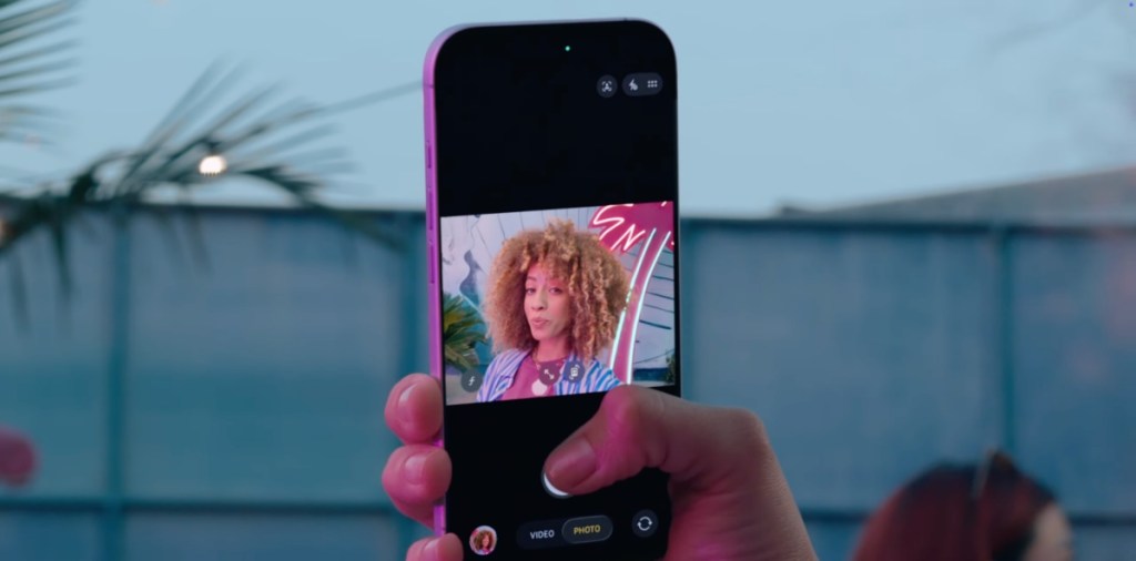 A woman taking selfie in landscape view on iPhone 17