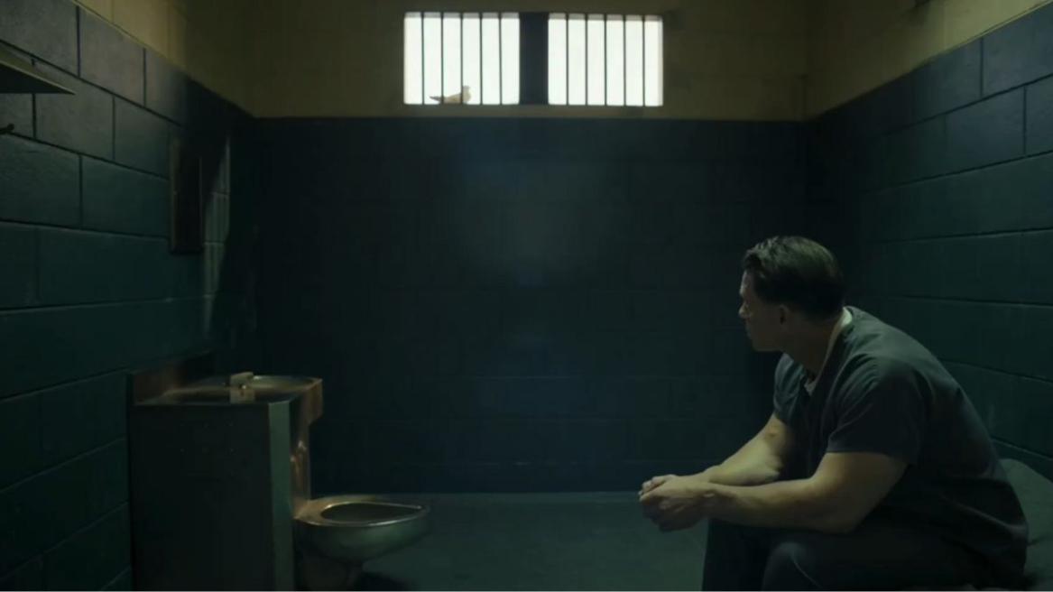 Peacemaker being held in a holding cell